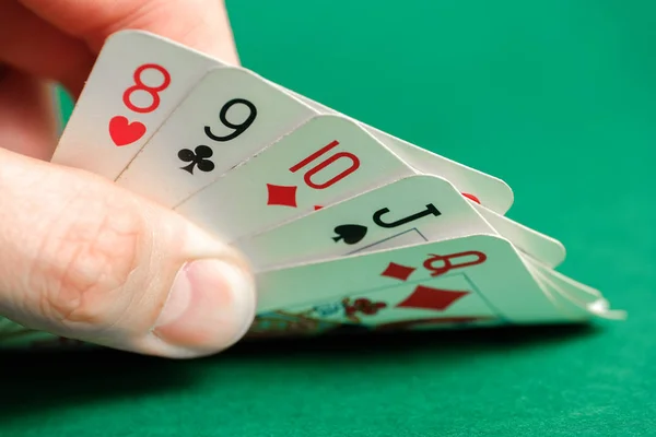 Hand holds a combination in poker - straight on a green background.