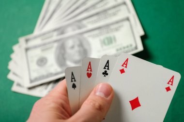 El dolar ile yeşil bir arka plan üzerinde dört as tutar.