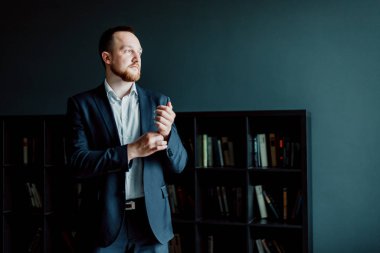 takım elbiseli başarılı işadamı ofiste duruyor ve düğmeleri bir düğme.