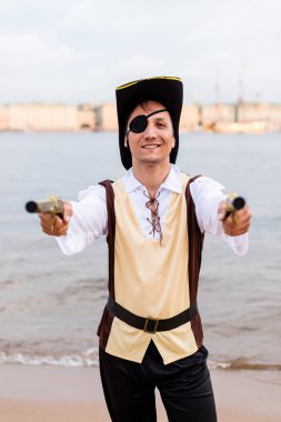 Korsan kostümlü gülümseyen adam iki oyuncak silahı merceğe doğrulttun.