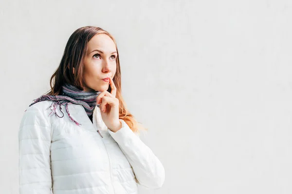 Caucasian girl putting finger to the corner of her mouth with slight smirk. — Stock Photo, Image