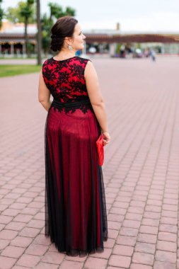 Zemin uzunluğunda siyah ve kırmızı elbise artı boyutu modeli kaldırımda geri döndü.