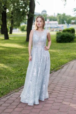 Yaz parkında zarif açık gri boncuklu zemin uzunlukta elbise ince sarışın kız.