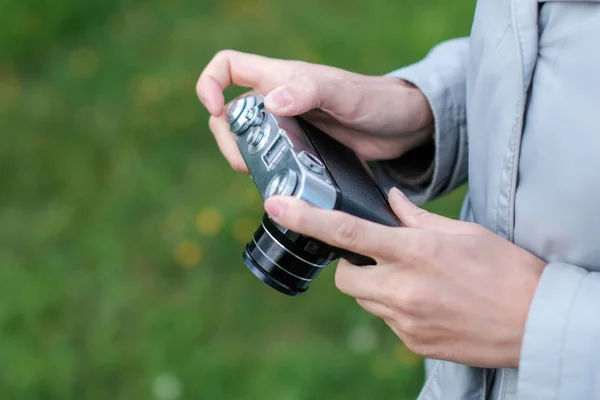 Vrouwelijke handen houden retro fotocamera op achtergrond gras. — Stockfoto