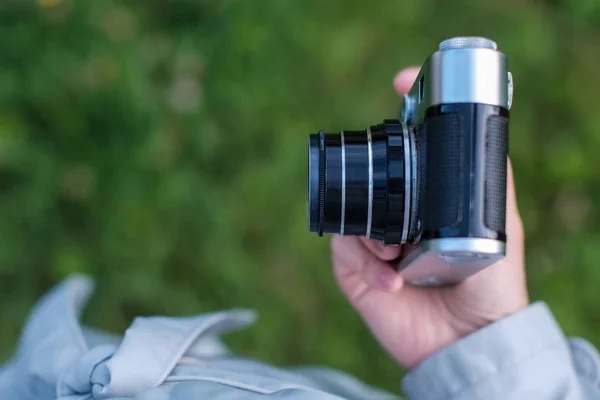 Weibliche Hand mit Retro-Fotokamera auf Gras im Hintergrund. oben — Stockfoto