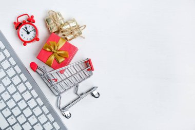 Noel online alışveriş konsepti. Kırmızı saat, tramvay ve ahşap arka plan üzerinde hediye ile beyaz klavye. Düz yatıyordu.