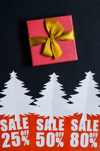 Árvores de Natal de papel com cartões de desconto vermelhos e uma caixa de presentes em um papel preto whatman. Conceito de venda de Natal . — Fotografia de Stock