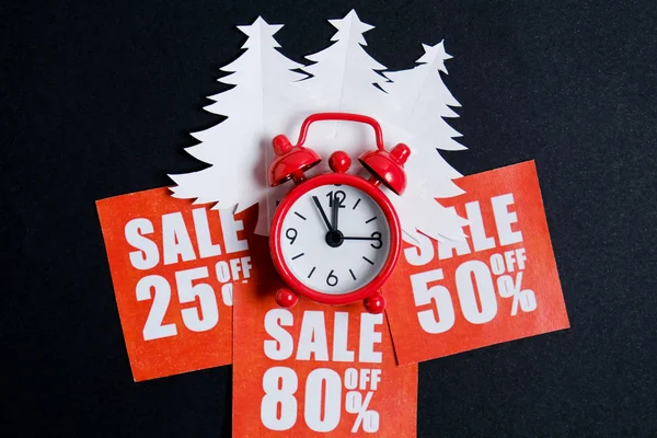 Árvores de Natal feitas de papel branco em placas vermelhas com descontos e um relógio vintage em um papel whatman em preto. Conceito de venda de Natal . — Fotografia de Stock