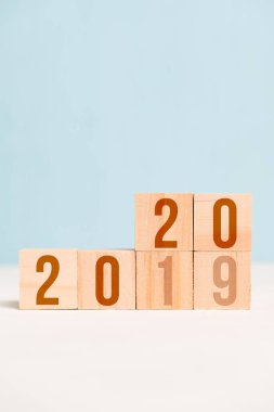 Mavi arka planda tahta küplerde 2020 ve 2019 numaralar. Yıl değişimi konsepti. Dikey. Boşluğu kopyala.