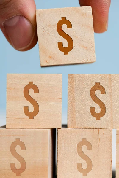 Los dedos sostienen cubos con un signo de dólar estadounidense sobre un fondo azul. El concepto de la acumulación de dinero, capital. De cerca. . — Foto de Stock