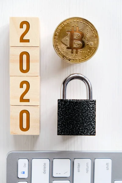 Bitcoin mit Zahlen 2020 auf Würfeln auf einem weißen Tastatur-Holzhintergrund ein Schloss. Sicherheitskonzept für Kryptowährungen im neuen Jahr. flach lag. Kopierraum. — Stockfoto