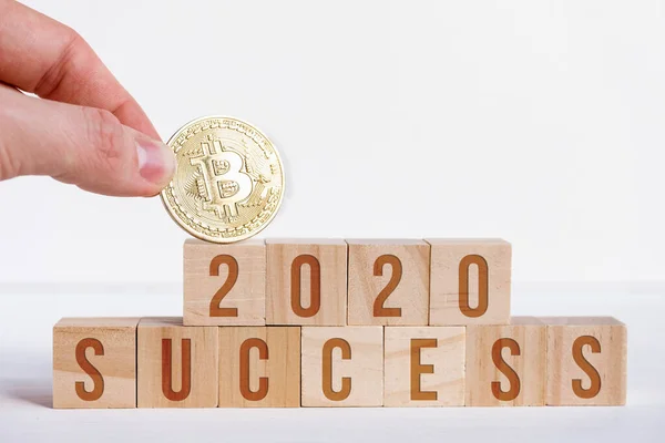 Bitcoin mit 2020-Zahlen auf Würfeln auf weißem Holzgrund mit den Buchstaben Erfolg. das Konzept von Erfolg und Popularität im neuen Jahr der Kryptowährung. — Stockfoto