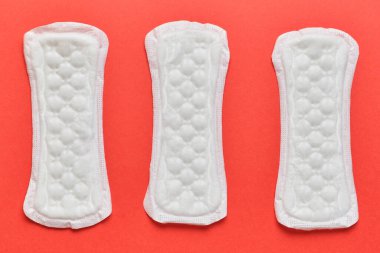 Kırmızı arka planda üç kadın pedi.