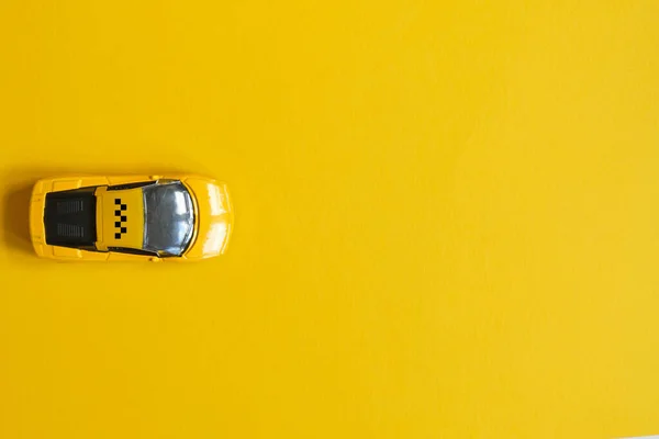 Toy taxi car on a yellow background with copy space