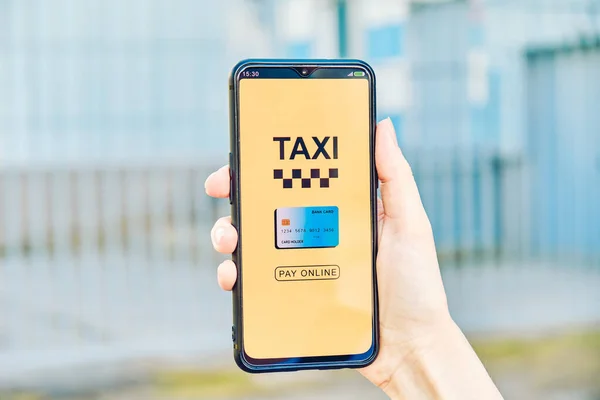Smartphone with taxi app for choosing online credit card payment in hand.