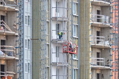 İşçiler yeni bir modern iskan binasında balkon inşa ediyorlar..