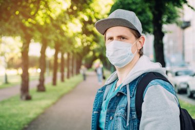 Şehirde kopyalanmış bir salgın sırasında tıbbi maske ve şapka takan beyaz bir adamın portresi. Yeni normal.