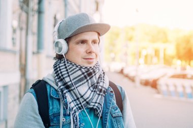 Gri şapkalı beyaz adam kulaklıkla müzik dinliyor..
