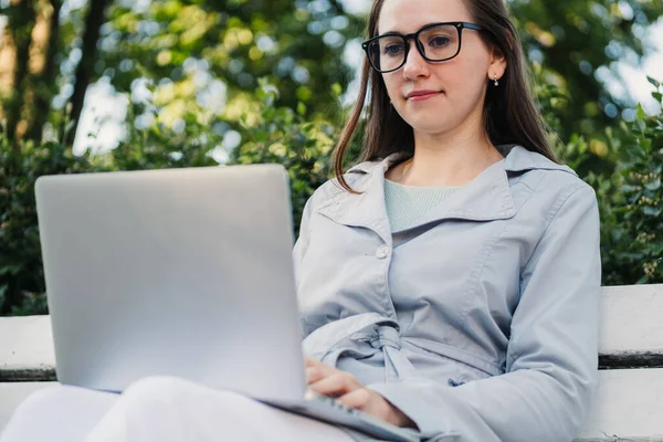 戴眼镜的白人女孩坐在城里 膝上型电脑 — 图库照片