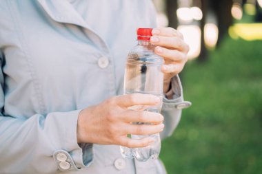 Beyaz kız ellerinde plastik su tutuyor.