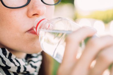 Beyaz kız plastikten su içiyor. Yakından..