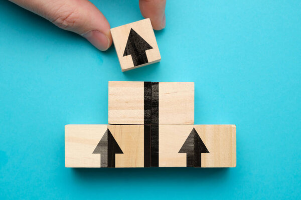 The concept of growth and business success. Wooden cubes pyramid with arrow on a blue background