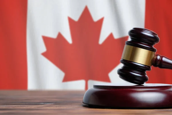 Justice and court concept in Canada. Judge hammer on a flag background.