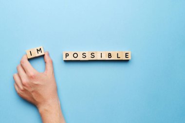 İmkansızdan olanak kavramı. Elin ahşap bloklu mavi bir arka planda olsun