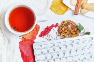 Kurumuş yapraklar üzerinde klavye, süveter üzerinde çay ile sonbahar konsepti.