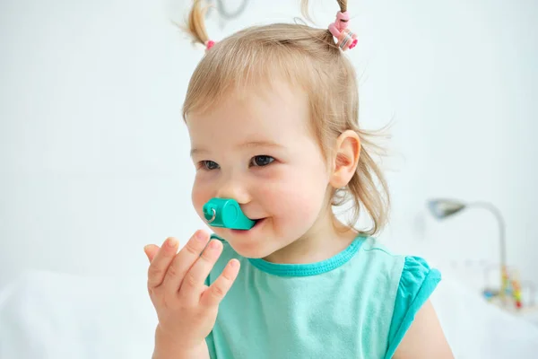 Happy and smiling toddler playing with a toy whistle.