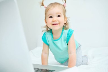 Şanslı çocuk laptopun yanındaki yatakta oturuyor.