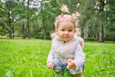 Bebek çimenlerde oturuyor yaz parkında yürüyor.