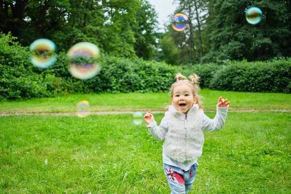 Uma Criança Sorridente Perseguindo Bolhas Sabão Através Parque Verão — Fotografia de Stock