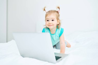 Kafkas bebek laptopun yanında yatağında oturuyor..