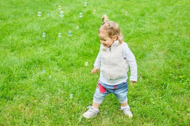 Yazın yeşil çimlerde yürüyen beyaz çocuk..