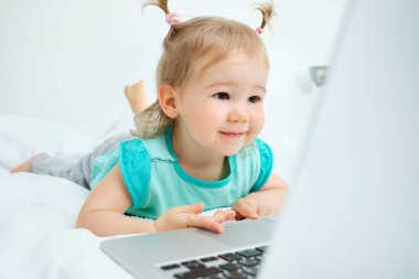 Kafkasyalı çocuk yatağa uzanıyor ve dizüstü bilgisayar kullanıyor..