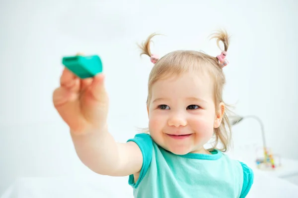 Caucasian kid smiling and showing toy whistle.