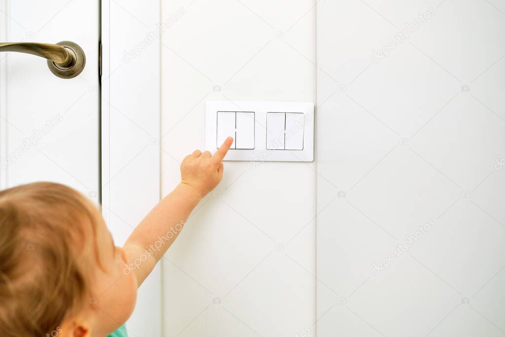 Caucasian kid uses light switch hand in home.