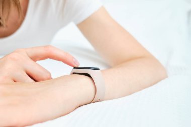 Kız evde oturuyor ve akıllı saat tebligatına bakıyor.