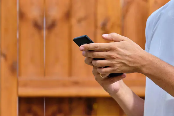 Person scrolls hand in smartphone on the street.