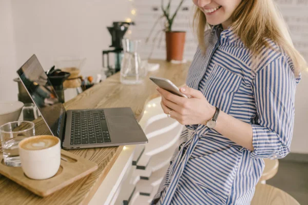 İşkadını el laptop ve kahve ile gülümseyen içinde akıllı telefon