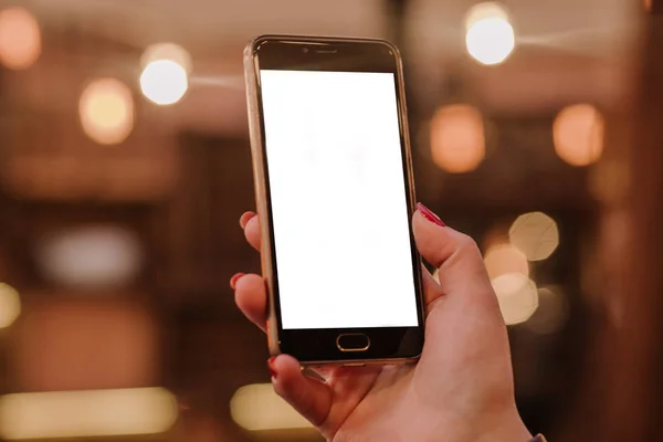 Kadın el ışık kırmızı ve beyaz bokeh arka plan ile bir akıllı telefon kullanarak kapatın