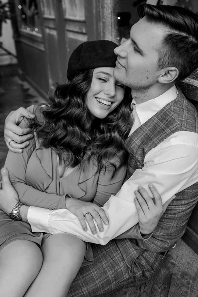 Retrato de pareja francesa con estilo en el exterior de la cafetería. Vintage escaparate francés está detrás. Foto en blanco y negro —  Fotos de Stock