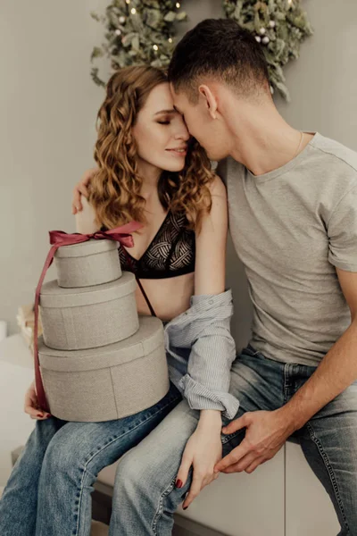 Wat een prachtig cadeau. Gelukkig jonge vrouw is opening vak en glimlachen. Man is zitten en haar met liefde te omarmen. Focus ligt op het geschenk — Stockfoto