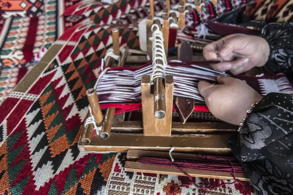 Kadınların elleri arkasında eski bir ahşap craftswoman, Arap halı arka plan üzerinde tezgah.