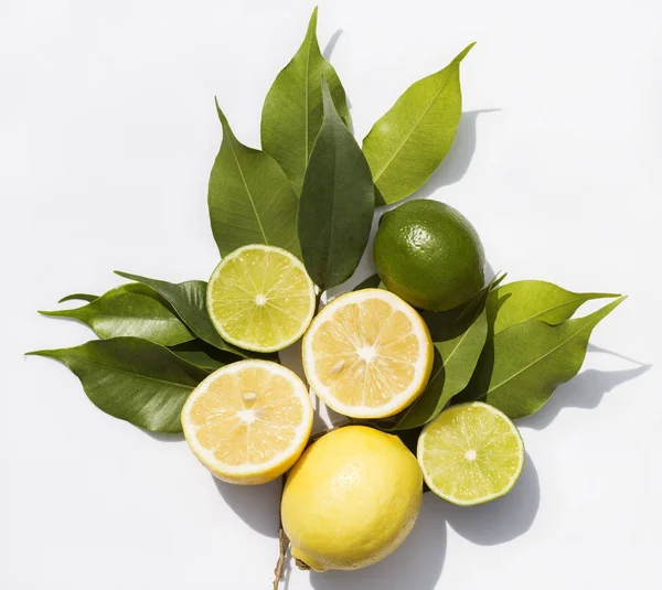 Lemons and limes with the green leaves on white background