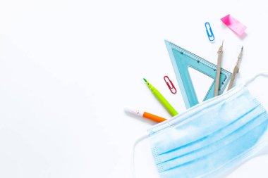 Okul malzemeleri koruyucu maske takıyor.