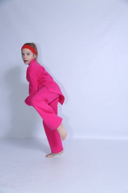 Pembe kimono küçük kız beyaz arka plan üzerinde egzersizler yapıyor