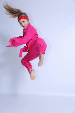Pembe kimono küçük kız beyaz arka plan üzerinde egzersizler yapıyor