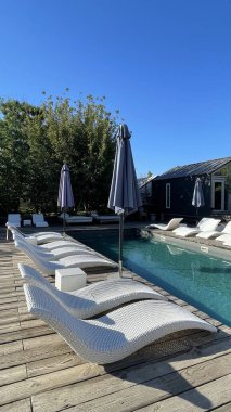Otel havuzunun yanındaki güneş pansiyonları. Yüzme havuzunun yanında boş güneş pansiyonları. Beyaz plastik güneş pansiyonları açık mavi yüzme havuzunun yanındaki açık hava oteli avlusunda. Yaz tatili kavramı